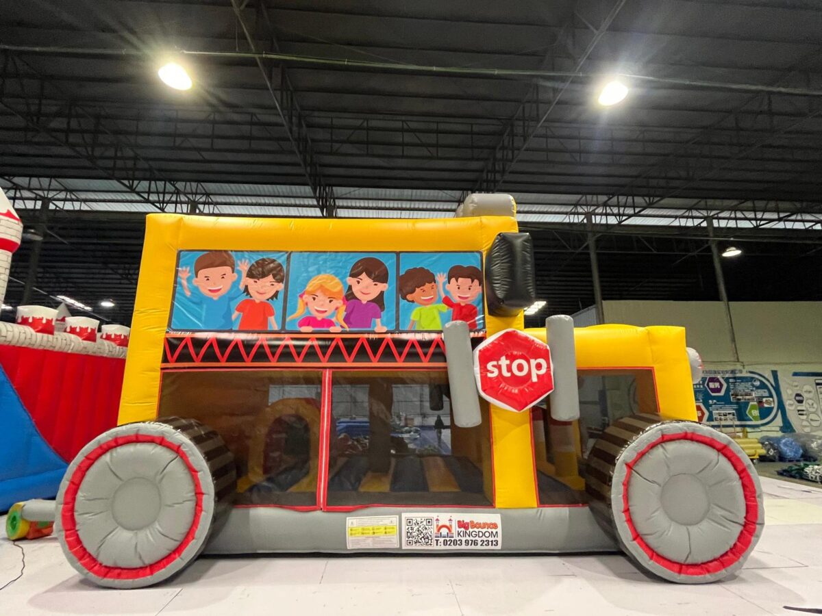 Yellow school bus bouncy castle with slide and cartoon children, available for hire in Abbots Langley